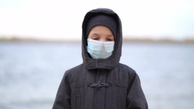Çocuk tıbbi maskesi ikinci dalga karantina sırasında sahilde duruyor. Coronavirus COVID-19 salgını sırasında.