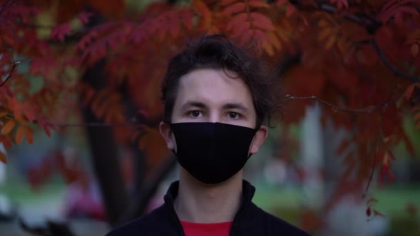Портрет подростка на улицах города в течение дня в маске против пандемии COVID-19 второй волны карантина — стоковое видео