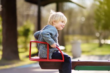 Küçük çocuk atlıkarınca açık sahada eğleniyor. Bahar ya da çocuklar için sonbahar aktif spor eğlence. Anaokulu veya okul bahçesinde. Yürümeye başlayan çocuk etkinlik