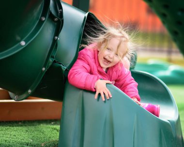Sevimli küçük kız açık sahada eğleniyor. İlkbahar/Yaz/Sonbahar aktif spor eğlence çocuklar için. Çocuk Plastik slayt üzerinde