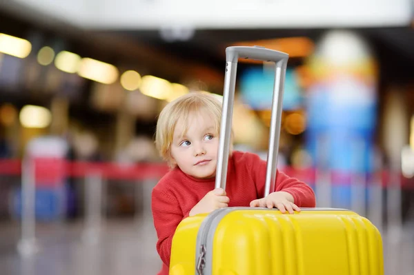 可爱快乐的小男孩与大黄色手提箱在国际机场飞行前 迷人的孩子在候机楼等着登机 家庭旅行以孩子概念 — 图库照片
