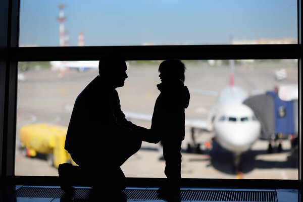 Man with little boy having fun at the international airport. Father with his cute little son waiting boarding. Family travel or immigration concept