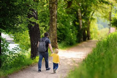 Neşeli küçük çocuk ve babası sıcak yaz günü zevk. Anne-baba ve öğrenci okul öncesi anaokuluna gidiyor. Etkin aile Park'ta yürüyordunuz. Dinlenme ve çocukluk kavramı. Anne-baba ve öğrenci okul öncesi anaokuluna gidiyor