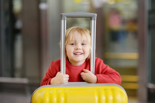 可爱快乐的小男孩与大黄色手提箱在国际机场飞行前 迷人的孩子在候机楼等着登机 家庭旅行以孩子概念 — 图库照片