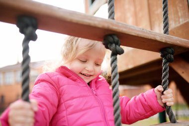 Sevimli küçük kız açık sahada eğleniyor. İlkbahar/Yaz/Sonbahar aktif spor eğlence çocuklar için. Çocuk oyun için açık havada ahşap donanımları