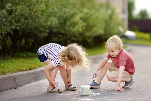 Mutlu erkek ve kız ile renkli tebeşir asfalt üzerinde çizim. Yaratıcı eğlence yürümeye başlayan çocuk için. Sokak sanatı, çocuklar eğitim.