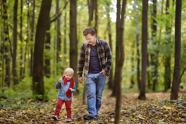 父亲和他的小儿子在远足活动期间在森林里日落 一家人在秋天的森林里散步 活跃或运动的休闲时间在自然 — 图库照片