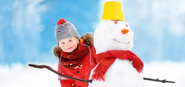 雪だるまを楽しんで赤冬の服の少年 冬の子どもたちとアクティブなアウトドア レジャー 雪に覆われた冬の公園で散歩中に子供します — ストック写真