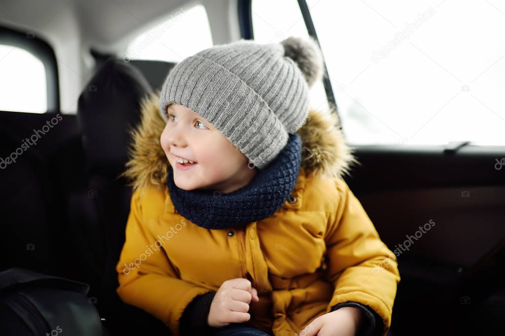 Portrait of pretty little boy sitting in car seat during roadtrip or travel. Family car travel with kids. Child transportation safety