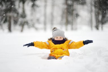 Eğleniyor kar kar yağışı sırasında şirin ufaklık. Aile ile çocuklar için açık kış aktiviteleri.