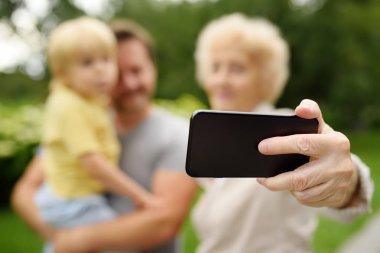 Parkta yürüyüş sırasında çoklu tarafından oluşturulan mutlu aile alarak selfie. Aile iletişim kavramları
