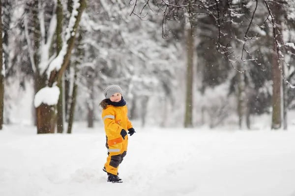 穿着黄色冬天衣服的可爱小男孩在下雪时走路 儿童户外冬季活动 — 图库照片