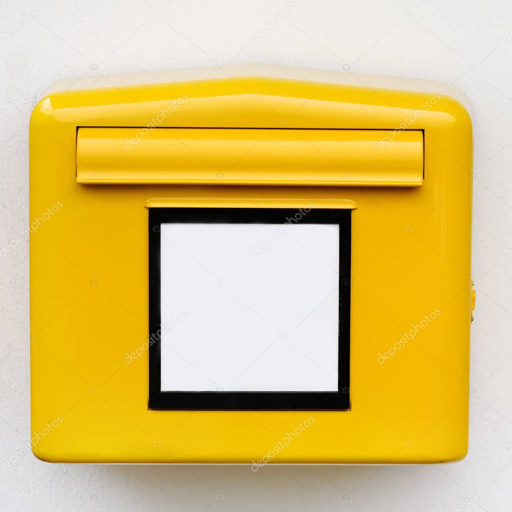 Yellow iron mailbox on white wall. Close-up photo of mail box with empty sign in Germany, Europe
