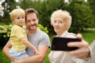 Parkta yürüyüş sırasında çoklu tarafından oluşturulan mutlu aile alarak selfie. Aile iletişim kavramları