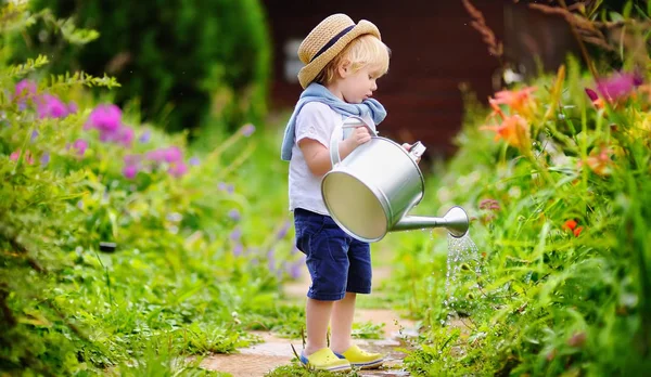 夏の晴れた日に庭で植物に水をまく麦藁帽子でかわいい幼児の少年 — ストック写真