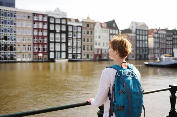 成熟的女人看着阿姆斯特丹著名的舞蹈屋在阳光明媚的日子 — 图库照片