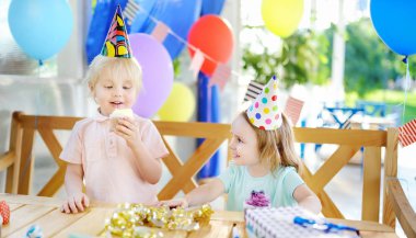 Sevimli küçük kız ve erkek eğlenceli ve renkli dekorasyon ve pasta doğum günü partisi kutlamak sahip. Şekerleme, çikolata, düdük/blower/boynuz ve şenlikli hediyeler ile çocuk. Okul öncesi ya da toddlers doğum günü partisi.