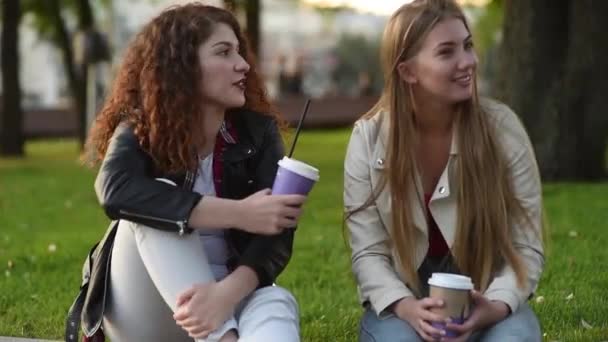 两个漂亮的年轻女子在户外聊天和喝咖啡 沟通和流言蜚语 — 图库视频影像