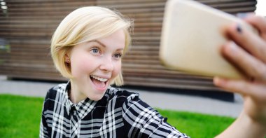 Genç kadın alarak akıllı telefon ile açık havada kendi kendine portre (selfie)