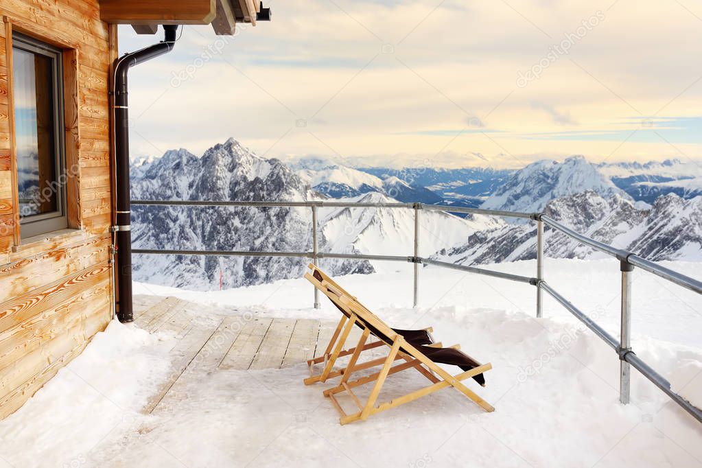 Sunbeds on the terrace of the Alpine Chalet house in the mountains. Winter vacation in Alps .