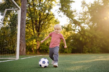 Küçük çocuk yaz gününde bir futbol/futbol oyunu oynarken eğleniyor. Etkin açık havada oyun/spor çocuklar için. Çocuklar futbol sınıfları ve kampları