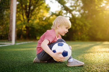 Küçük çocuk yaz gününde bir futbol/futbol oyunu oynarken eğleniyor. Etkin açık havada oyun/spor çocuklar için. Çocuklar futbol sınıfları ve kampları