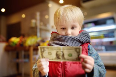 Küçük çocuk bir dolarlık para birimi Not tutar. Çocuklar ve para kavramı. Para işleme eğitimi.