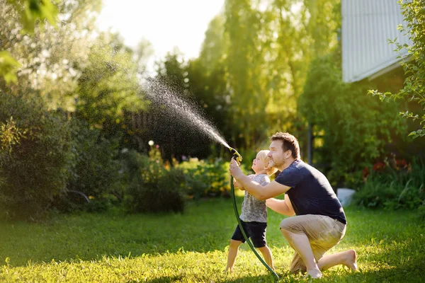 Divertido Niño Pequeño Con Padre Jugando Con Manguera Jardín Patio —  Fotos de Stock