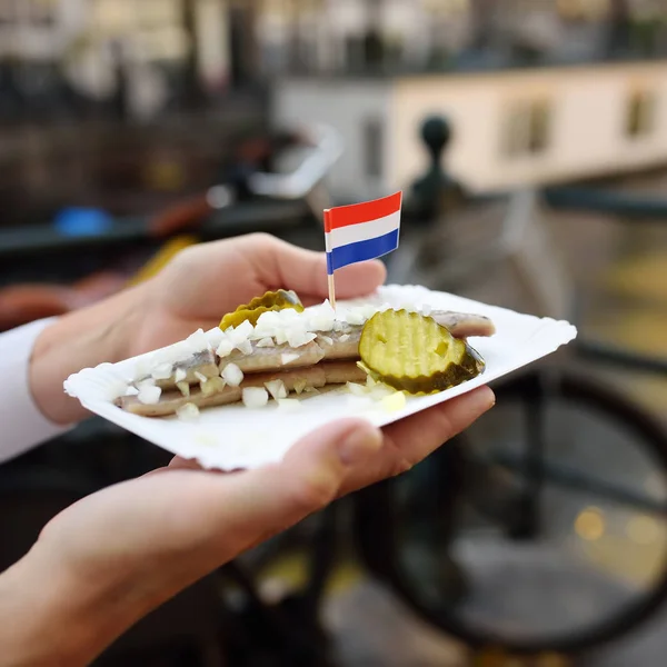 女性は アムステルダム オランダのファーストフード市場でプレート有名なニシン魚玉ねぎとキュウリを保持します 伝統的なオランダ料理 — ストック写真