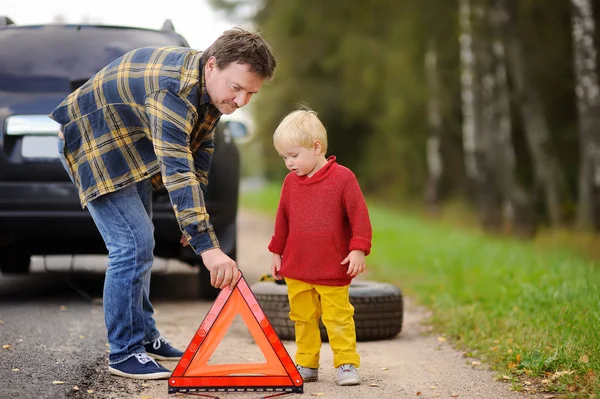 父亲和他的小儿子修理汽车和改变车轮一起在夏季的一天 家庭的在路边的两个等待汽车修理 — 图库照片