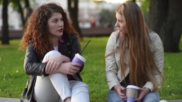 两个漂亮的年轻女子在户外聊天和喝咖啡 沟通和流言蜚语 — 图库视频影像