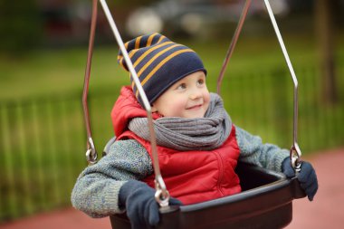 Sevimli küçük çocuk açık sahada eğleniyor. İlkbahar/Yaz/Sonbahar aktif spor eğlence çocuklar için. Alt salıncak üzerinde