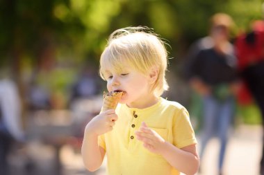 Cute little boy eating Ice-Cream gelato outdoors. Sweets/sugar food for little kids.