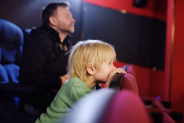 Sevimli küçük çocuk babasıyla çizgi film sinema izliyor. Çocuklarla aile için bir dinlence/eğlence.