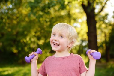 Sevimli küçük çocuk açık havada halter kaldırma. Çocuk spor.