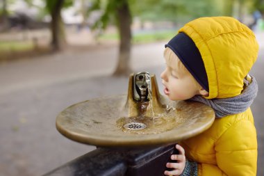 Central Park'ta, Manhattan, New York, ABD yürüyüş sırasında şehir Fountain küçük çocuk içme suyu. Aile ile çocuk Nyc yürür.
