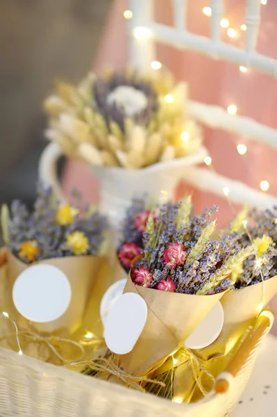 Beautiful dried flowers in paper boxes with lights on background. Wedding decorations close up. Floral design.