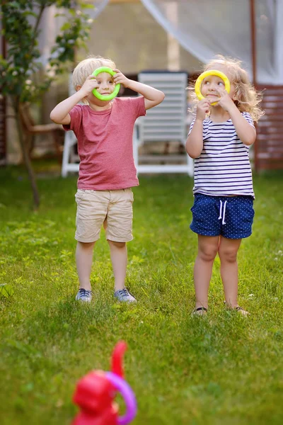 可爱的小男孩和女孩在游戏中扔戒指在夏天的户外 夏季户外活动为有孩子的家庭举办的游戏 — 图库照片