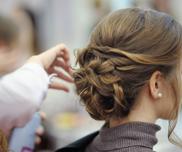 Young woman/bride getting her hair done before wedding or party. Wedding or prom ball hairstyles.