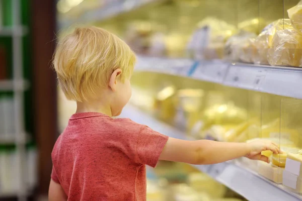 チーズとバター 新鮮な乳製品を選択するスーパー マーケットや食料品店でかわいい男の子 子供を持つ若い家族の健康的なライフ スタイル — ストック写真