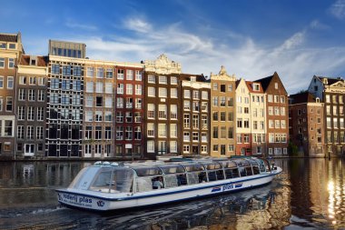 Amsterdam, Hollanda - 17 Eylül 2018: Amsterdam'ın ünlü dans eden evler ve nehir tekne güneşli yaz gününde ön planda. Hollanda gezi. Turizm ve seyahat Holland tarafından.