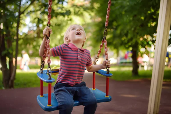 Sevimli küçük çocuk açık sahada eğleniyor. Çocuklar için yaz aktif spor eğlence. Alt salıncak üzerinde