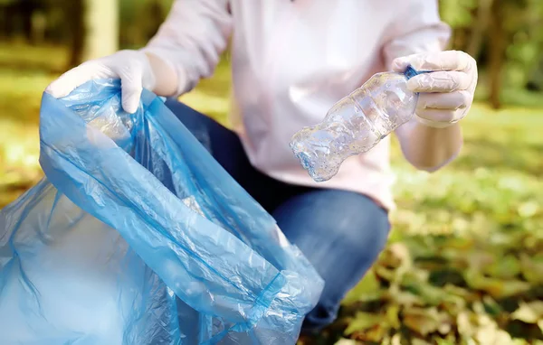 Gönüllü plastik çöp ve açık havada üzerinde biyolojik olarak parçalanabilen çöp kutusuna koyarak. Ekoloji, geri dönüşüm ve doğa kavramı korunması.