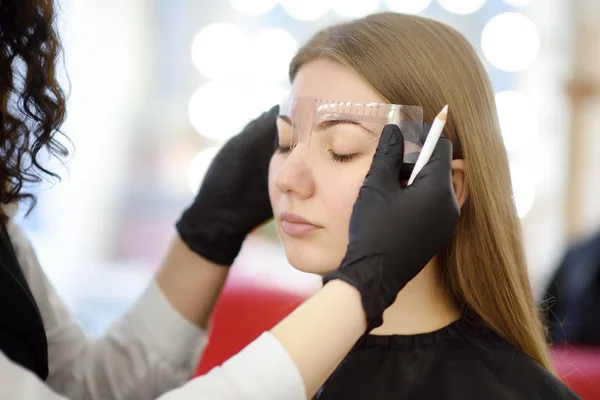 美容师做眉毛化妆。有吸引力的妇女在美容院接受面部护理。建筑眉毛. — 图库照片