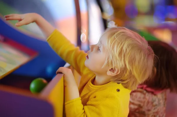 A kisfiú a szórakozás a játék Center szórakoztató. Gyerek játszik a pénznyerő automata Arcade központjában. — Stock Fotó