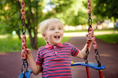 Sevimli küçük çocuk açık sahada eğleniyor. Alt salıncak üzerinde