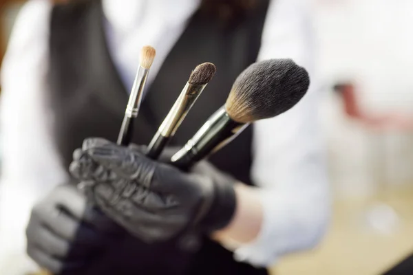 Kosmetikerin zeigt Pinsel für Make-up und bereitet sie für den Einsatz vor. Nahaufnahme. Gesichtspflege und Make-up im professionellen Salon — Stockfoto