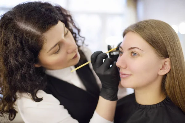 Cosmetologist φρύδια ζωγραφική με πινέλο. Ελκυστική γυναίκα να πάρει περιποίηση προσώπου και μακιγιάζ στο σαλόνι ομορφιάς. Αρχιτεκτονική φρύδια. — Φωτογραφία Αρχείου