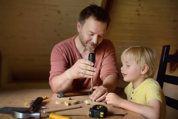 Volwassen man en zoontje samen een houten speelgoed. Vader leren zijn zoon werk met tools. Traditionele onderwijs van jongen. Familie waarden. Papa's opvoeding. — Stockfoto