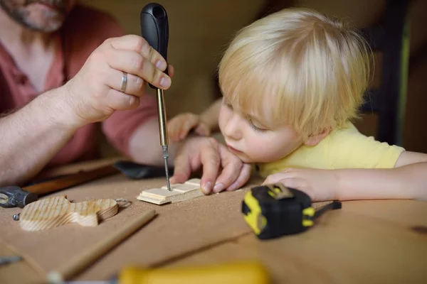 成熟的男人和小男孩一起做一个木制玩具。父亲学习他的儿子用工具工作。男孩的传统教育。家庭的价值观。爸爸的教养特写. — 图库照片